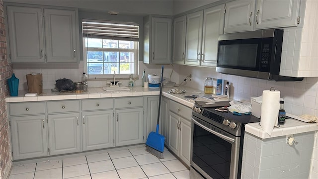 kitchen featuring gray cabinetry, appliances with stainless steel finishes, sink, and backsplash