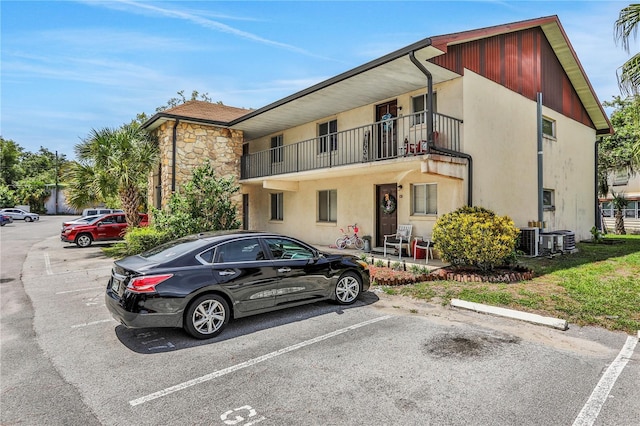 view of property with uncovered parking and central AC unit