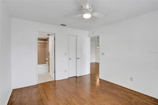 unfurnished bedroom with a textured ceiling, baseboards, and wood finished floors