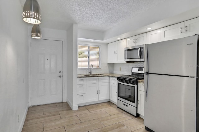 kitchen with appliances with stainless steel finishes, white cabinets, a sink, and wood finish floors