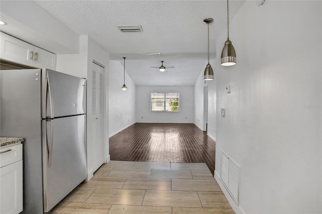 kitchen featuring wood finish floors, visible vents, white cabinetry, freestanding refrigerator, and pendant lighting