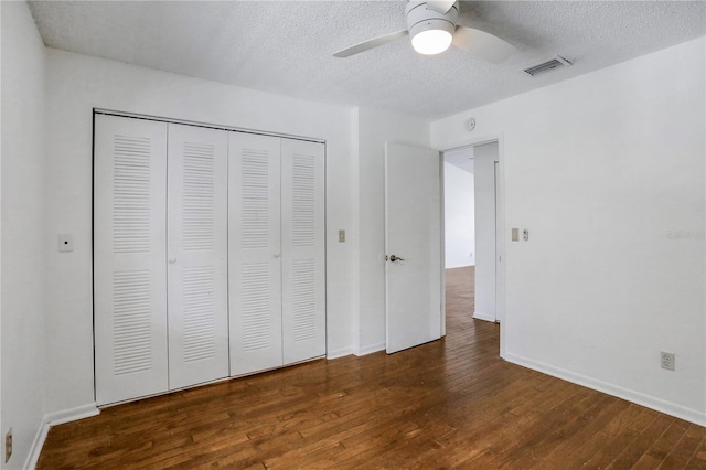 unfurnished bedroom featuring a textured ceiling, visible vents, baseboards, a closet, and dark wood finished floors