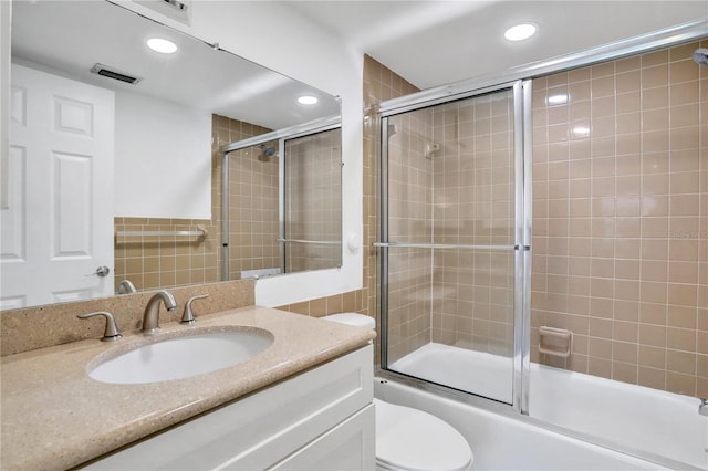 bathroom featuring toilet, recessed lighting, bath / shower combo with glass door, visible vents, and vanity