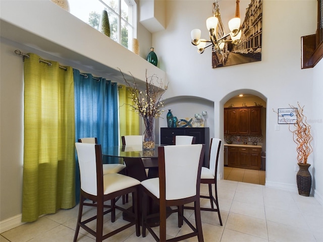 tiled dining area featuring a towering ceiling and a chandelier