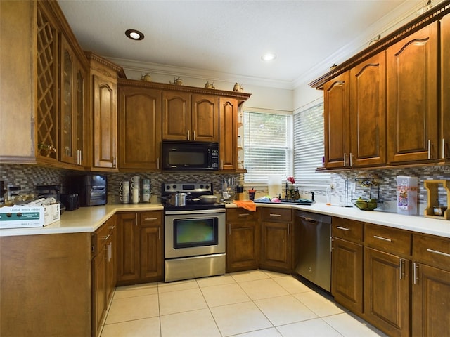 kitchen featuring decorative backsplash, crown molding, light tile patterned flooring, stainless steel appliances, and sink