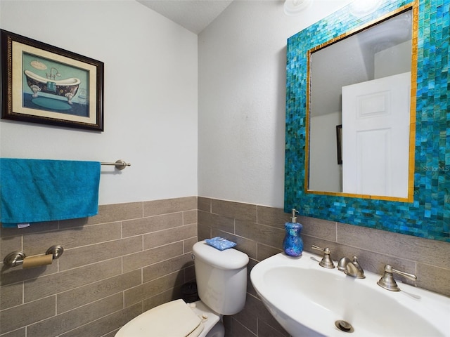 bathroom featuring tile walls, backsplash, toilet, and sink