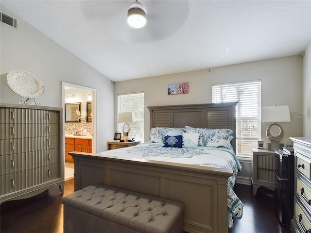 bedroom with ensuite bath, lofted ceiling, dark hardwood / wood-style flooring, a textured ceiling, and ceiling fan