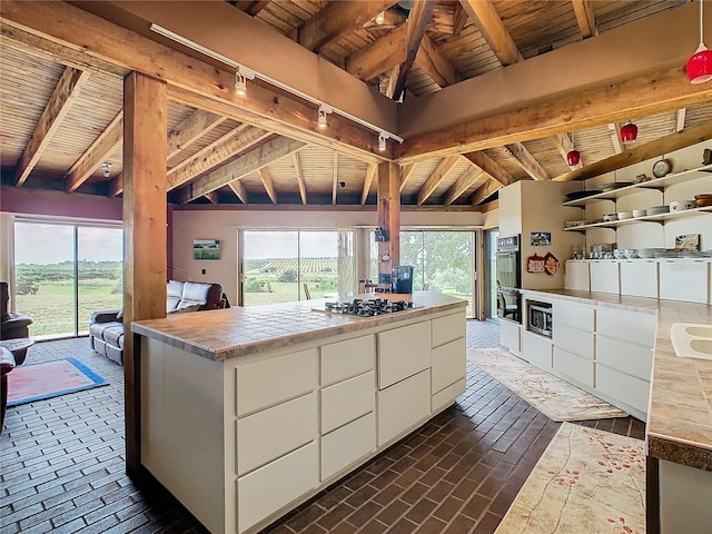 kitchen featuring appliances with stainless steel finishes, wooden ceiling, vaulted ceiling with beams, and white cabinetry