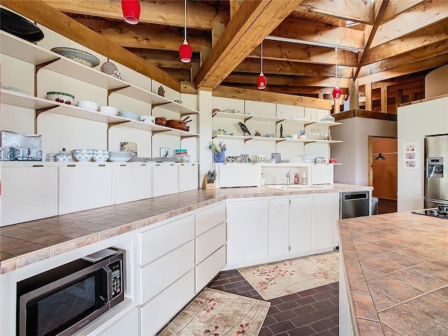 2741 Edwards Rd, Haines City, FL 33844 - kitchen with open shelves, stainless steel microwave, tile countertops, white cabinets, and beam ceiling
