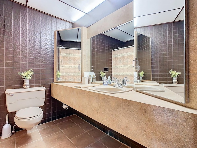 bathroom with tile walls, tile patterned flooring, sink, and toilet