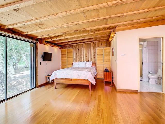 bedroom with tile patterned flooring, connected bathroom, access to exterior, and wooden walls