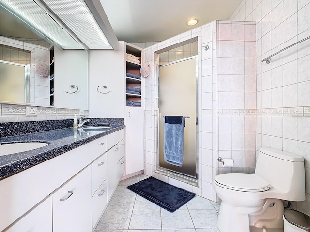 bathroom with tile walls, toilet, vanity, and tile patterned floors