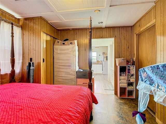 bedroom with wood walls, fridge, connected bathroom, and coffered ceiling