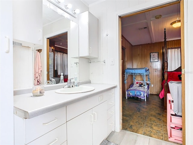 bathroom featuring wood walls, tile patterned floors, ornamental molding, and vanity