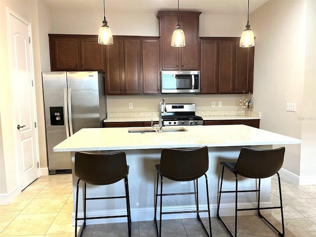 kitchen with an island with sink, stainless steel appliances, and light tile patterned floors