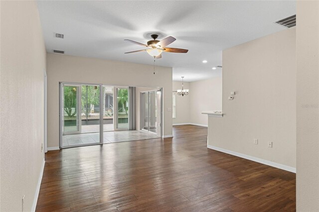 empty room with dark wood-type flooring and ceiling fan with notable chandelier