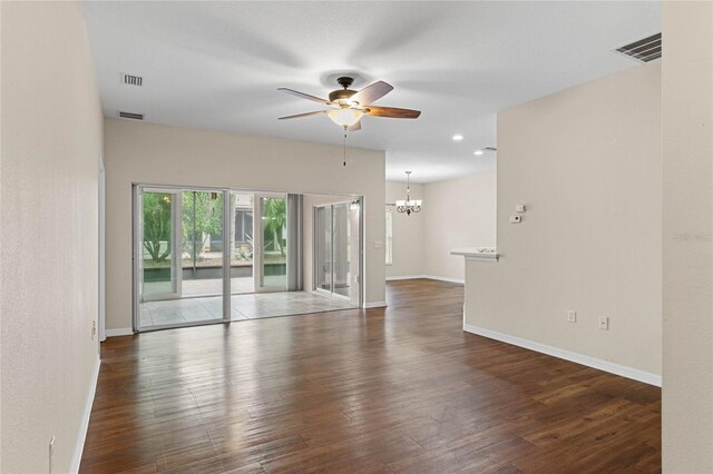 spare room with wood finished floors, ceiling fan with notable chandelier, visible vents, and baseboards