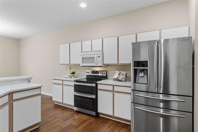 kitchen with dark wood-type flooring, baseboards, light countertops, white cabinets, and stainless steel appliances