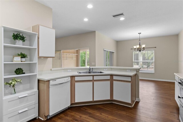 kitchen with white cabinets, white dishwasher, an inviting chandelier, dark wood-type flooring, and pendant lighting