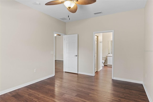 unfurnished bedroom featuring dark wood-style floors, visible vents, baseboards, ensuite bath, and ceiling fan