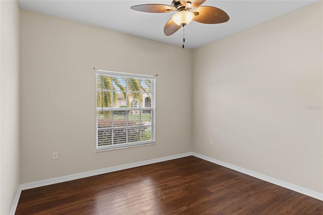 spare room featuring dark wood finished floors, a ceiling fan, and baseboards
