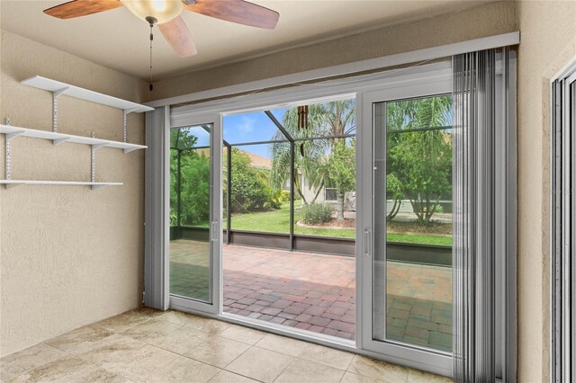 doorway with tile patterned flooring, a ceiling fan, and a textured wall