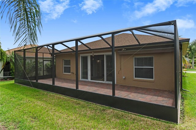 back of property featuring glass enclosure, a yard, and a patio area