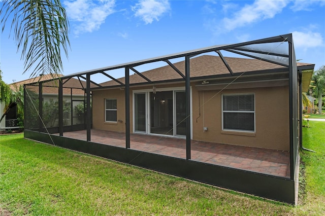 back of house featuring stucco siding, a lawn, glass enclosure, and a patio area