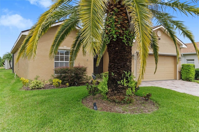 view of side of home with a garage, stucco siding, driveway, and a yard