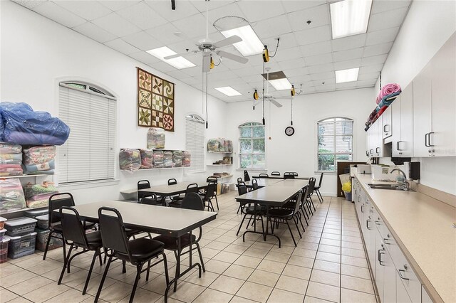 dining space with a paneled ceiling, ceiling fan, sink, and light tile patterned flooring