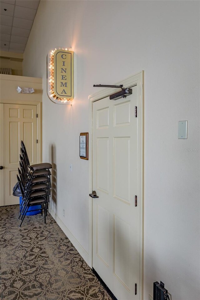 hall featuring carpet, baseboards, and a paneled ceiling