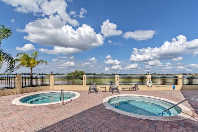 view of swimming pool with a patio, a community hot tub, and fence
