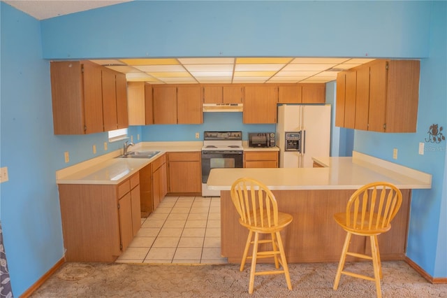 kitchen with light tile patterned floors, sink, kitchen peninsula, and white appliances