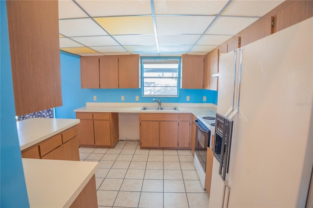 kitchen featuring sink, white appliances, light tile patterned flooring, and a drop ceiling