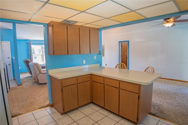 kitchen featuring kitchen peninsula, a paneled ceiling, ceiling fan, and light colored carpet