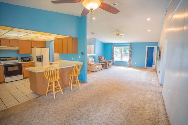 kitchen featuring white range with electric cooktop, refrigerator with ice dispenser, kitchen peninsula, a breakfast bar, and light carpet