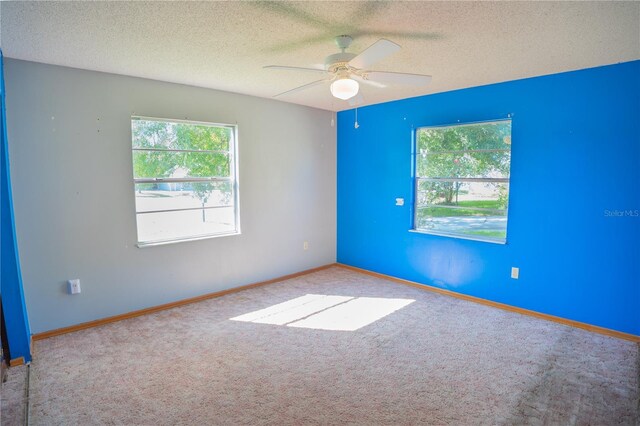 unfurnished room with ceiling fan, a textured ceiling, and light carpet