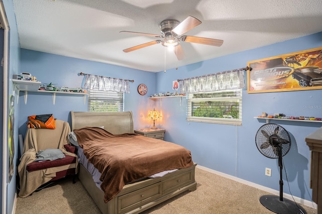 carpeted bedroom with ceiling fan, multiple windows, baseboards, and a textured ceiling