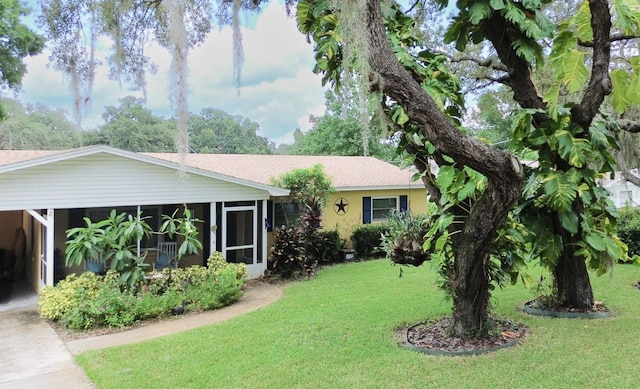 single story home with a sunroom, a front lawn, and a carport