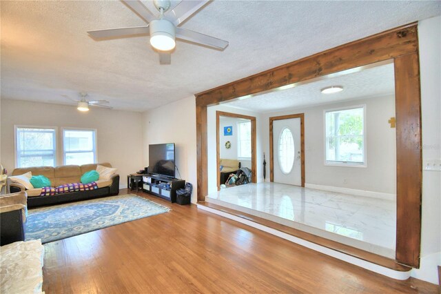 living room featuring ceiling fan, wood-type flooring, and a textured ceiling