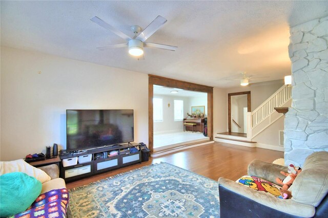 living room with a textured ceiling, ceiling fan, and hardwood / wood-style flooring