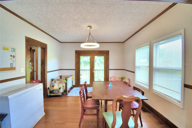 dining area featuring hardwood / wood-style flooring, crown molding, and french doors