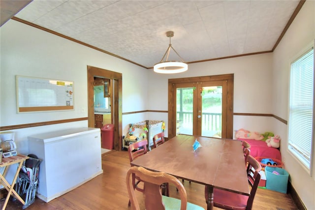 dining space with hardwood / wood-style floors, ornamental molding, and french doors