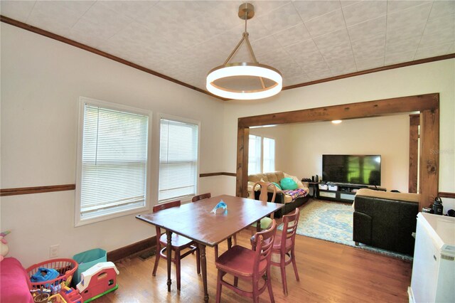 dining room featuring a wealth of natural light, crown molding, and wood-type flooring