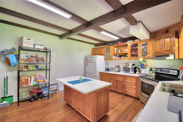 kitchen featuring a center island, sink, beamed ceiling, light wood-type flooring, and white appliances