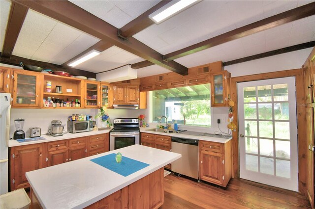 kitchen featuring light wood-type flooring, exhaust hood, sink, beamed ceiling, and stainless steel appliances