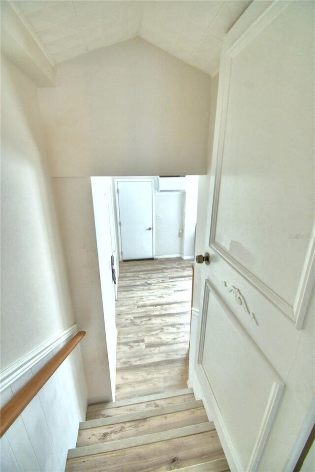 stairway with lofted ceiling and hardwood / wood-style flooring