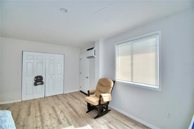 living area with light hardwood / wood-style flooring and a wall mounted air conditioner