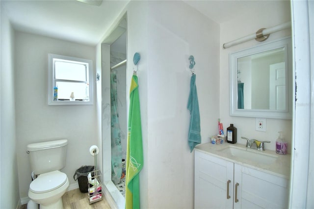 bathroom featuring toilet, hardwood / wood-style floors, a shower, and vanity