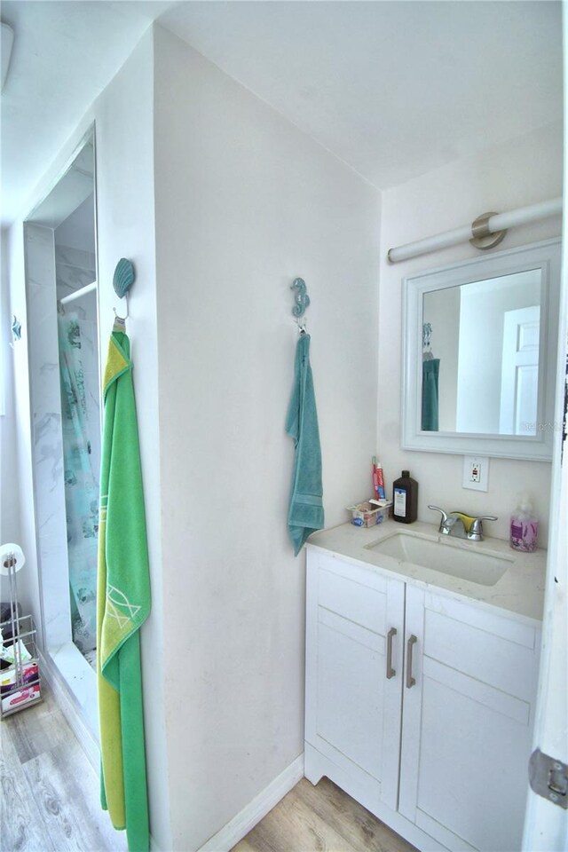 bathroom with hardwood / wood-style flooring, vanity, and a shower